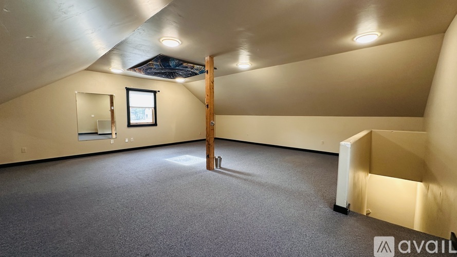 A spacious room with a grey carpet and a window.
