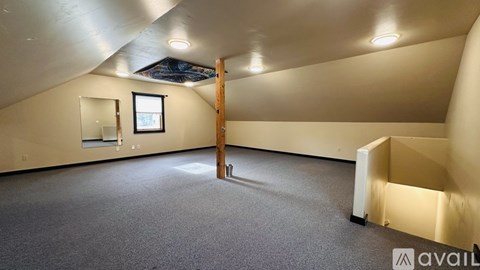 A spacious room with a grey carpet and a window.