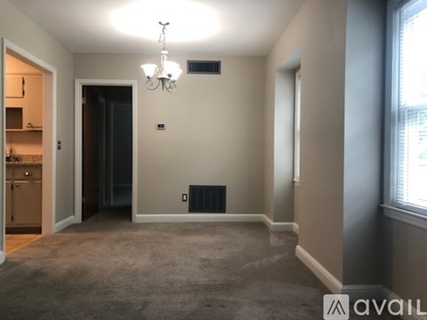 A room with a carpeted floor, a chandelier, and a window.