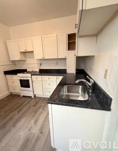 A kitchen with white cabinets and a black countertop.