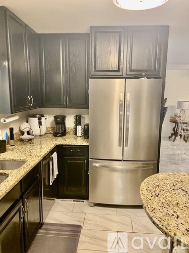A kitchen with a granite counter top and a stainless steel refrigerator.