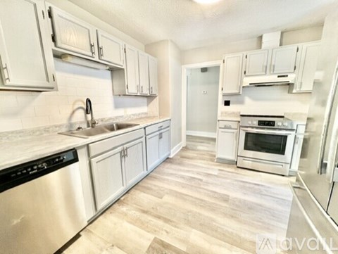 A kitchen with white cabinets and a wooden floor.