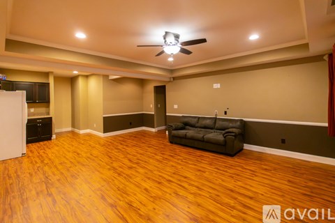A living room with a black couch and wooden floors.