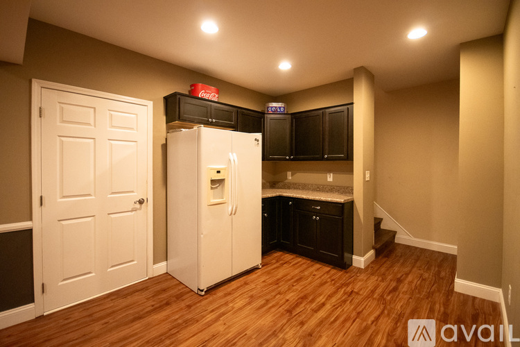 A small kitchen with wood flooring and a white refrigerator.