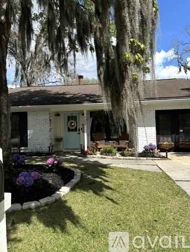 A white house with a blue door and a small garden in front.