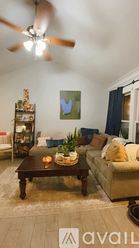 A living room with a ceiling fan and a painting on the wall.