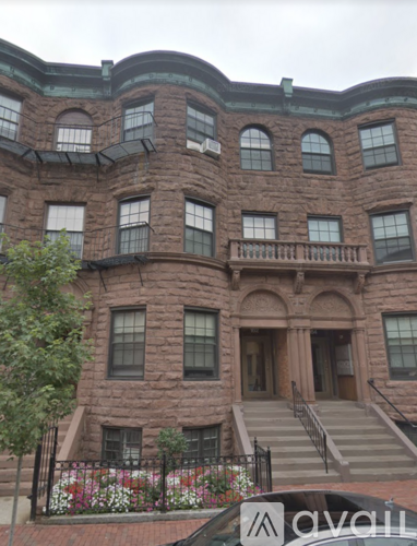 A large brown building with a black car in front of it.