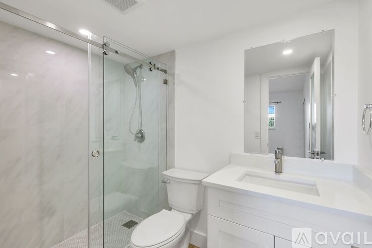 A white bathroom with a toilet, sink, and shower.