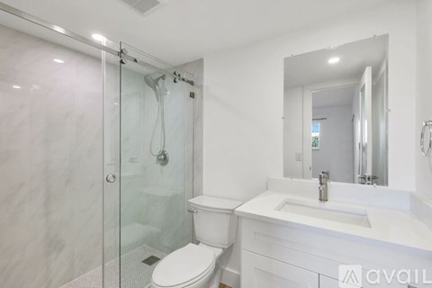 A white bathroom with a toilet, sink, and shower.