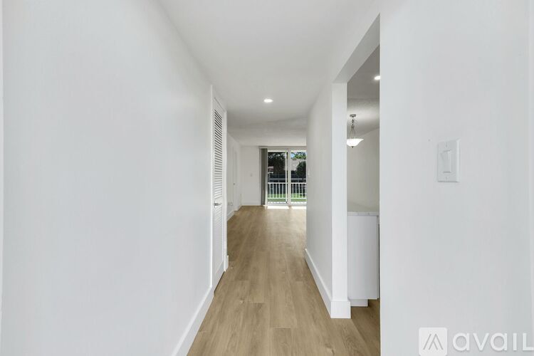 A long hallway with wood floors and white walls.