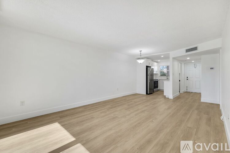 A spacious room with wooden flooring and white walls.