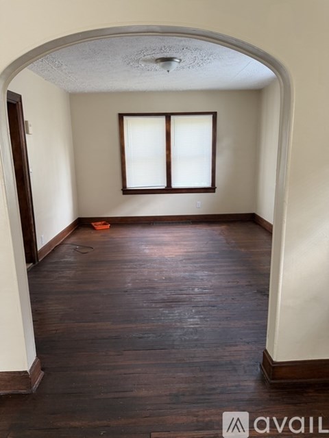 A room with wooden floors and a window with blinds.
