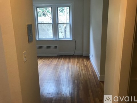 A room with wooden floors and a window with a view of trees outside.