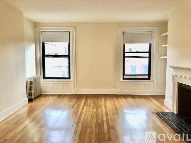 A room with wooden floors and two windows.