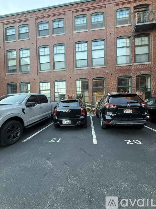 Two cars are parked in a parking lot in front of a brick building.