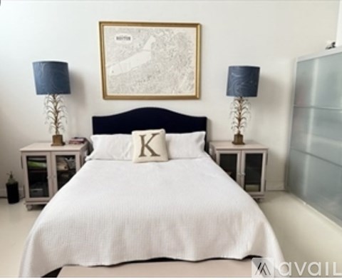 A bedroom with a white bed and two lamps on either side of the bed.