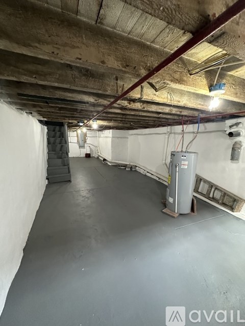 A spacious, unfinished basement with a concrete floor and exposed ceiling beams.