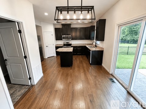 A kitchen with black cabinets and a wooden floor.