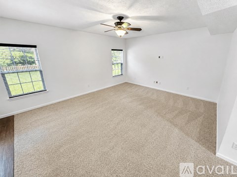 A spacious room with a ceiling fan and carpeted floor.