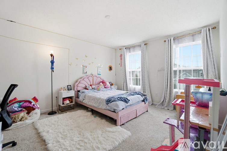A bedroom with a pink bed and a white rug.