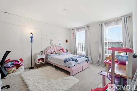 A bedroom with a pink bed and a white rug.