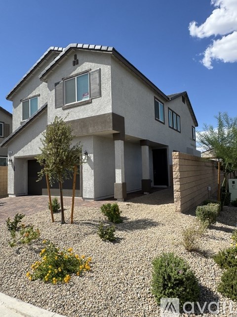 A modern house with a grey exterior and a gravel garden in front.