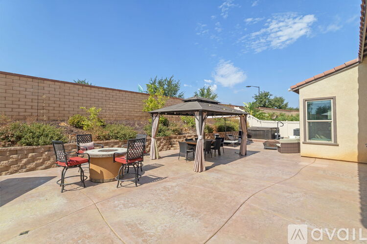 A patio with a table and chairs under a gazebo.