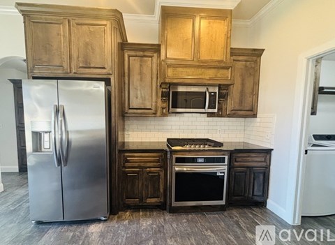 A kitchen with wooden cabinets and a stainless steel refrigerator.