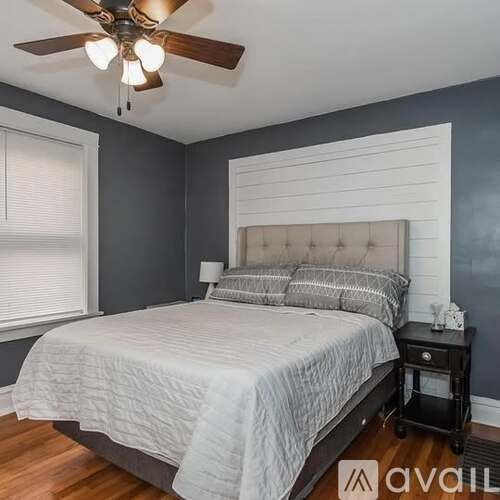 A bedroom with a bed, nightstand, and a ceiling fan.