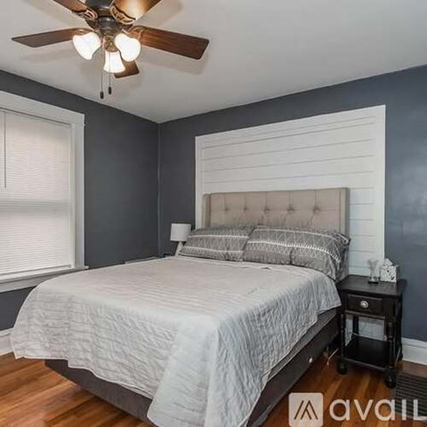 A bedroom with a bed, nightstand, and a ceiling fan.