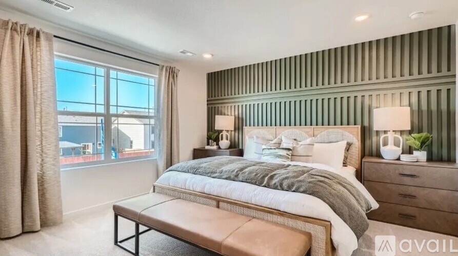 A bedroom with a large bed, a bench, and a window with curtains.