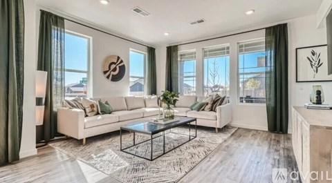 A modern living room with a white sofa, a glass coffee table, and a large window with green curtains.