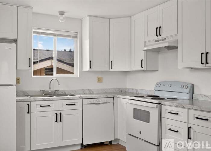 A kitchen with white cabinets and appliances.