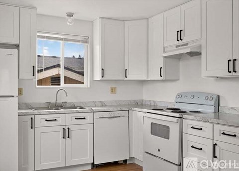 A kitchen with white cabinets and appliances.