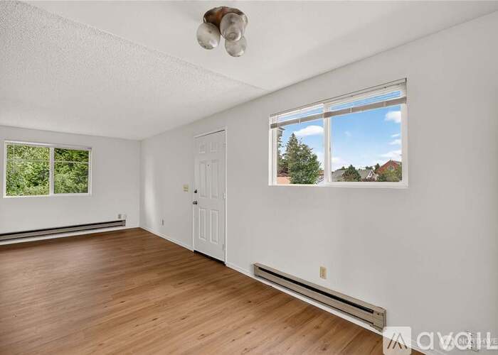 A room with a white door and a window showing a view of trees and houses outside.