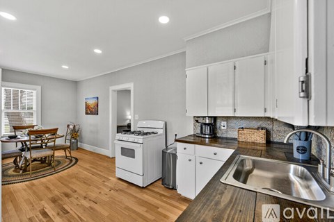 A kitchen with white cabinets and a wooden island.