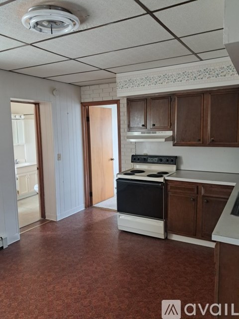 A kitchen with a stove top oven and wooden cabinets.
