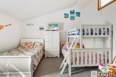 A white bedroom with two beds and a dresser.
