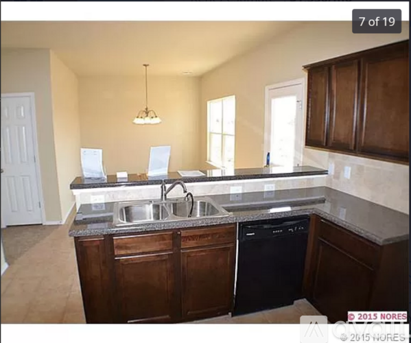 A kitchen with a black dishwasher and wooden cabinets.