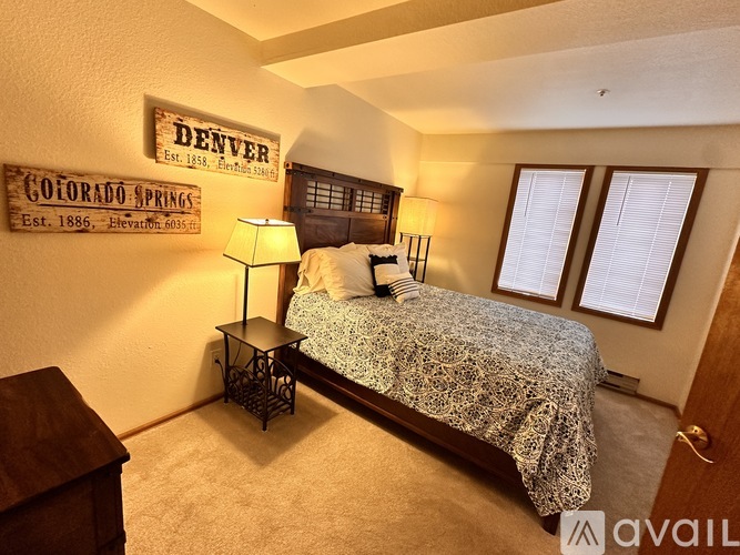 A bedroom with a bed, nightstand, and a sign on the wall.