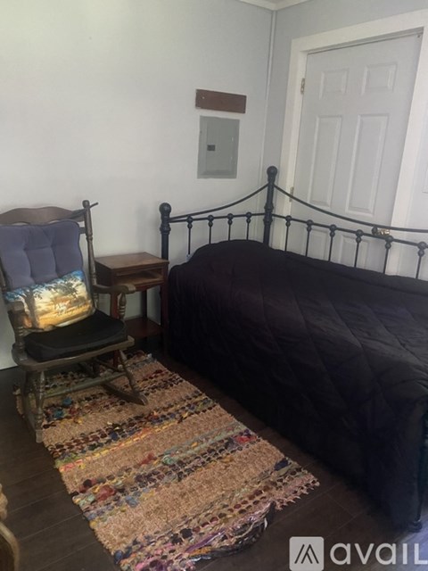 A bedroom with a bed, chair, and rug.