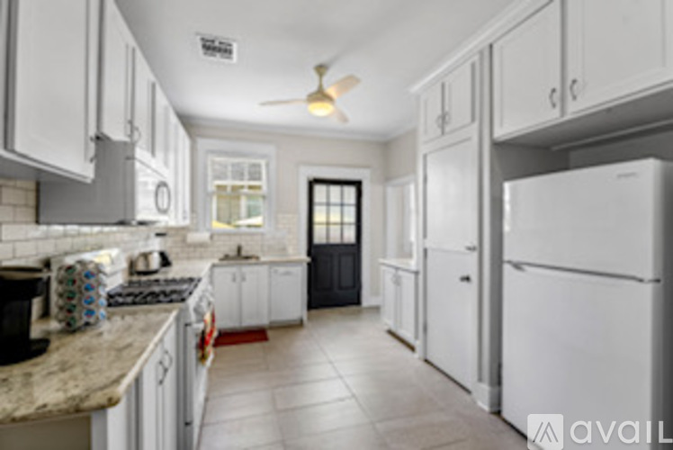 A kitchen with white cabinets and a black door.