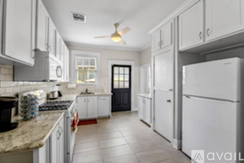 A kitchen with white cabinets and a black door.