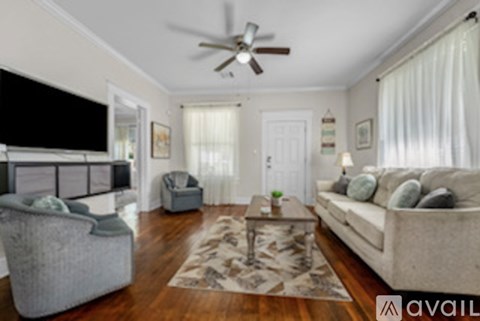 A living room with a grey couch, a grey armchair, a coffee table and a television.