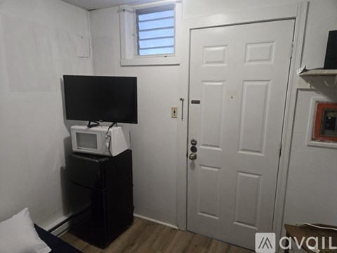 A black television sits on top of a black cabinet in a room with white walls.