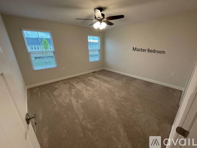 A room with a carpeted floor and a ceiling fan, labeled as the master bedroom.