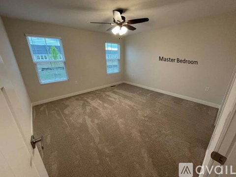 A room with a carpeted floor and a ceiling fan, labeled as the master bedroom.