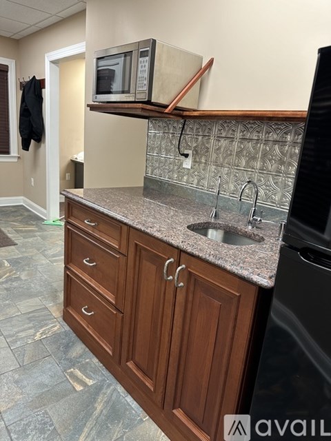 A kitchen with a black dishwasher and wooden cabinets.