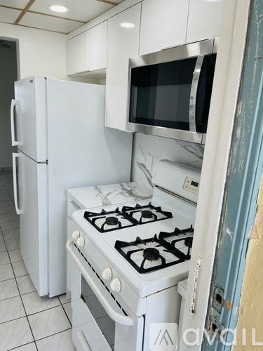 A white kitchen with a stove and a refrigerator.
