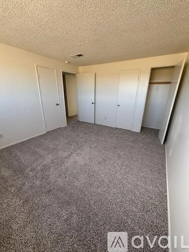 A room with grey carpet and white walls with a logo on the bottom right.
